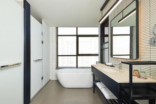a bathroom with a tub and a large window at Aloft Shijiazhuang in Shijiazhuang
