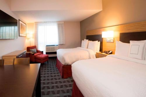 a hotel room with two beds and a chair at TownePlace Suites by Marriott Pittsburgh Cranberry Township in Cranberry Township