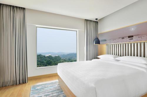 a bedroom with a large white bed and a large window at Four Points by Sheraton Kochi Infopark in Cochin