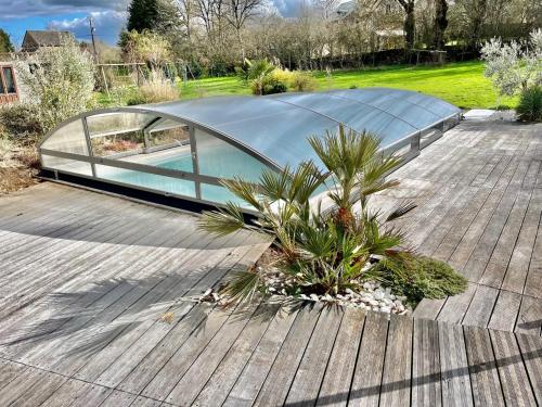 奧內萊沙托的住宿－Villa contemporaine avec piscine sur 4000 m2 à Rodez 9 personnes，木甲板上的玻璃房子,种植了植物