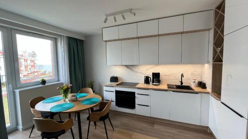 eine Küche mit einem Tisch, einem Tisch und Stühlen in der Unterkunft Resort Apartamenty Klifowa Rewal 55 in Rewal