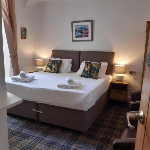 a bedroom with a bed with two towels on it at The Merrydale Guest House in Llandudno