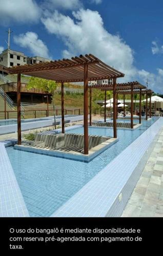 a swimming pool with a wooden pavilion on top of it at Apt próximo à praia de Ponta Negra/Litoral Sul/Natal in Parnamirim