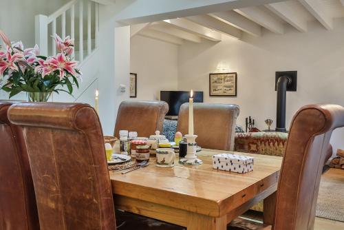 une salle à manger avec une table en bois et des fauteuils en cuir dans l'établissement Finest Retreats - Middle Warble Stables, à Mellor