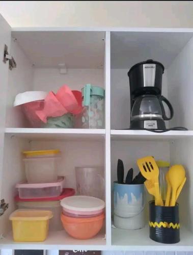 a white cabinet filled with dishes and utensils at Apt próximo à praia de Ponta Negra/Litoral Sul/Natal in Parnamirim
