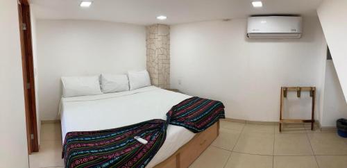 a small bedroom with a bed with white sheets at Palmas de Chahue in Santa Cruz Huatulco