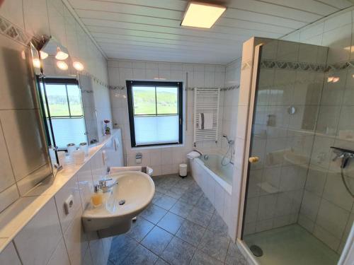 a bathroom with a sink and a shower and a tub at Ferienwohnung Weiherblick, Vulkaneifel in Mosbruch