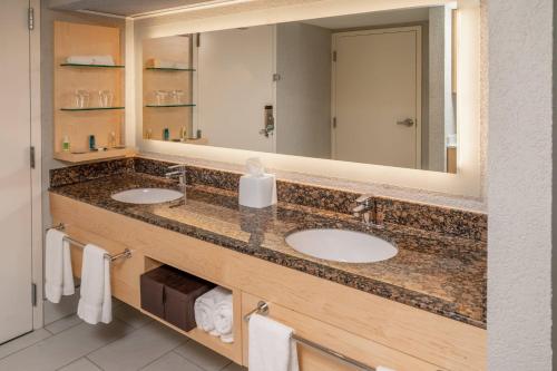 a bathroom with two sinks and a large mirror at Delta Hotels Huntington Downtown in Huntington