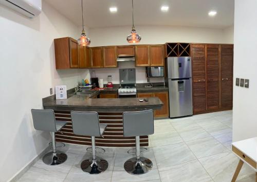a kitchen with wooden cabinets and a bar with chairs at Palmas de Chahue in Santa Cruz Huatulco