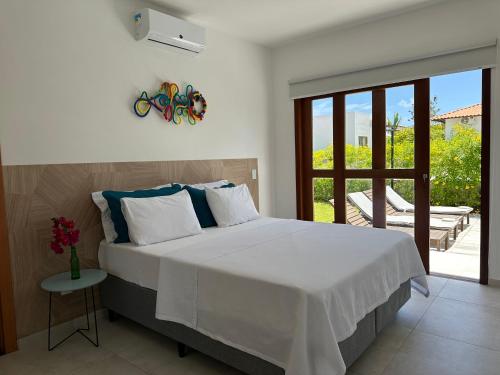 a bedroom with a large white bed and a balcony at Casa Ibiza - Pipa ''Luxurious 3-Bedroom Villa with pool'' in Pipa