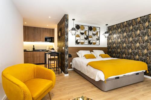 a bedroom with a bed and a chair and a kitchen at Marinha Grande Apartamentos N3 GOLD in Marinha Grande