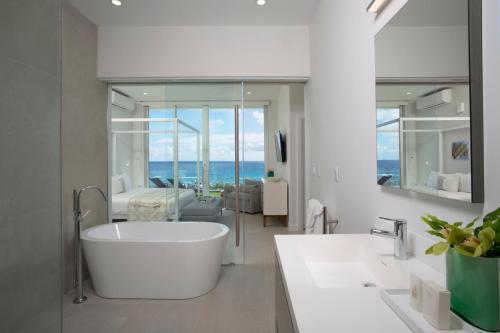 a white bathroom with a tub and a living room at Azura Bermuda in Bermuda