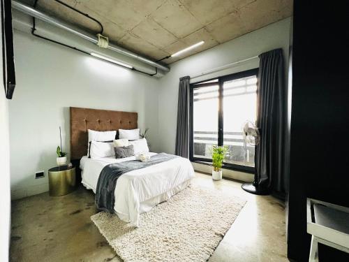 een slaapkamer met een bed en een groot raam bij Hallmark Apartment Urban City Stay in Johannesburg