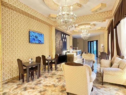 a living room with chairs and tables and a chandelier at Istanbul Gold Hotel in Baku