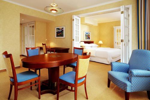 a hotel room with a table and chairs and a bed at Sheraton Essen Hotel in Essen