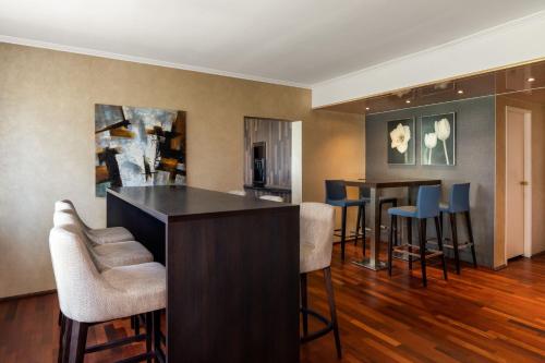 a living room with a bar and stools at Sheraton Essen Hotel in Essen