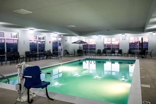 una piscina con una silla azul, mesas y sillas en Fairfield by Marriott Inn & Suites Louisville Airport en Louisville