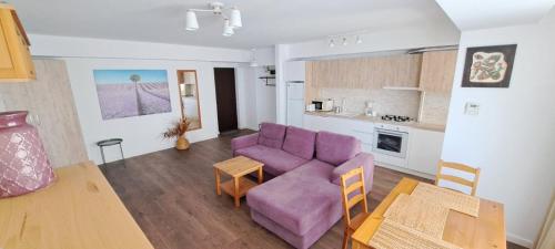 a living room with a purple couch and a table at C&Y Zev Apartments in Mamaia