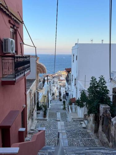 un vicolo con edifici e l'oceano sullo sfondo di La Casa Verde a Ermoupoli