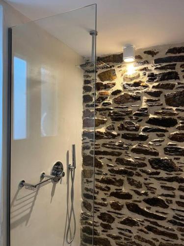 una doccia in vetro in un bagno con una parete in pietra di La Casa Verde a Ermoupoli