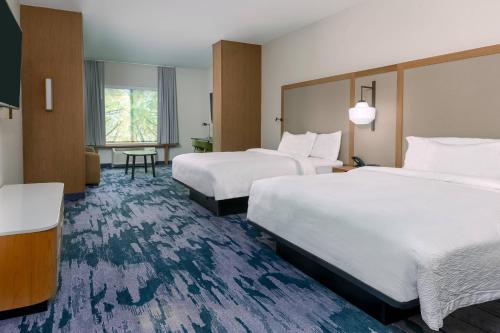 a hotel room with two beds and a table at Fairfield Inn & Suites Charlotte Monroe in Monroe