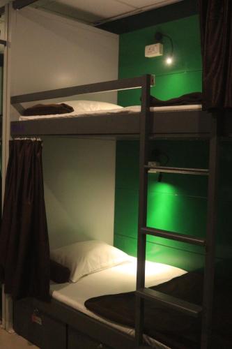 a room with three bunk beds with a green wall at Forrest Hostels in Mumbai