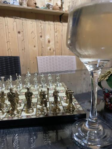 a glass of wine next to a table with chessitures at Casa bunicilor din Leresti in Voineşti