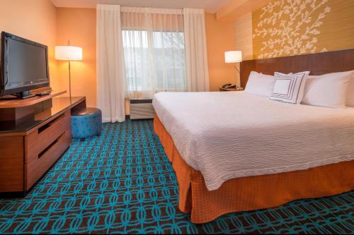 a hotel room with a bed and a flat screen tv at Fairfield Inn & Suites by Marriott Frederick in Frederick