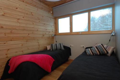 2 camas en una habitación con paredes y ventanas de madera en Otepää Holiday Home en Otepää