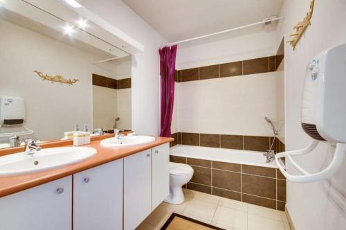 łazienka z 2 umywalkami, toaletą i wanną w obiekcie Agréable Appartement 3* non loin de l’Océan w mieście Biscarrosse