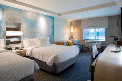 a hotel room with two beds and a chair and a desk at Courtyard by Marriott New York Queens/Fresh Meadows in Queens