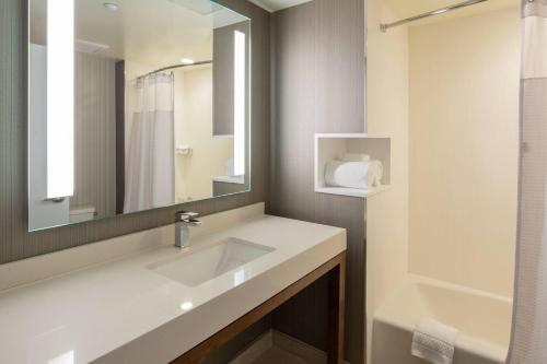 a bathroom with a sink and a mirror at Courtyard by Marriott New York Queens/Fresh Meadows in Queens