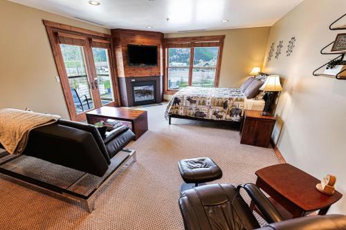 a bedroom with a bed and a living room with a fireplace at Large Studio Condo with Full Kitchen, Bike the Trail, Beautiful Balcony Views Hottub Fireplace in Kellogg