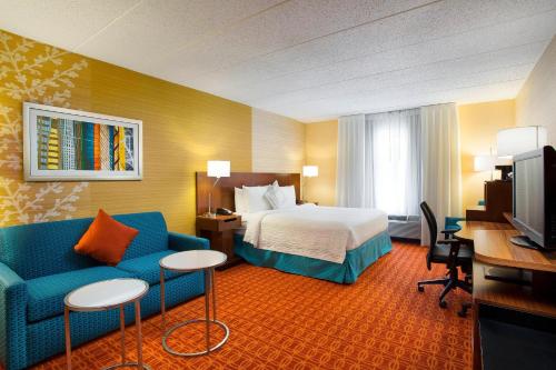 a hotel room with a bed and a blue couch at Fairfield Inn & Suites Chicago Midway Airport in Bedford Park