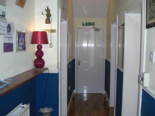 a hallway with a white door and a red lamp at Lynebank House Hotel, Bed & Breakfast in Carlisle