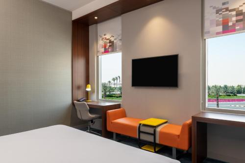 a hotel room with a bed and a desk and a tv at Aloft Dubai South in Dubai