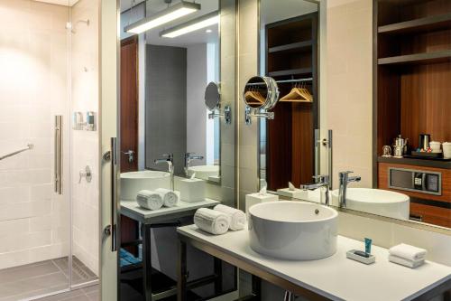 baño con 2 lavabos y espejo grande en Aloft Dubai South, en Dubái