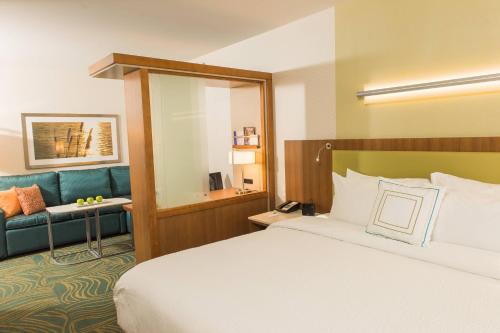 Habitación de hotel con cama y sofá azul en SpringHill Suites by Marriott Buffalo Airport en Williamsville