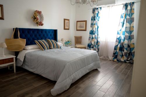 a bedroom with a bed with a blue headboard and a window at Villa Cinzia-150 mt from the beach in Mondello