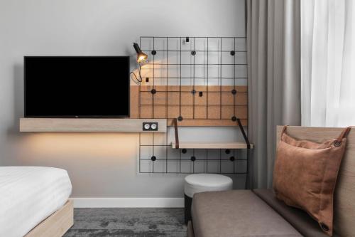 een woonkamer met een tv en een stoel bij Moxy Amiens in Amiens