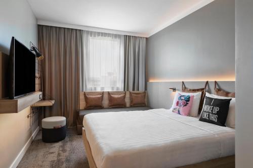 アミアンにあるMoxy Amiensのベッド1台、薄型テレビが備わるホテルルームです。