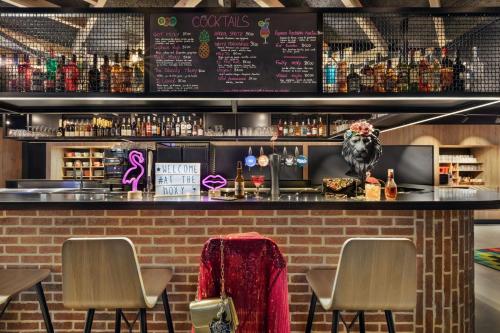 a bar with two chairs and a counter with drinks at Moxy Amiens in Amiens