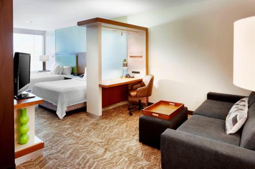 SpringHill Suites by Marriott Columbus OSU في كولومبوس: غرفة في الفندق بها سرير وأريكة ومكتب