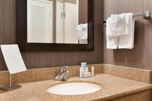 a bathroom with a sink and a mirror and towels at Courtyard by Marriott Bloomington Normal in Bloomington