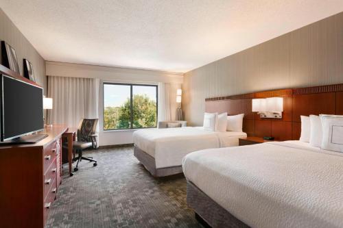 a hotel room with two beds and a flat screen tv at Courtyard by Marriott Bloomington Normal in Bloomington