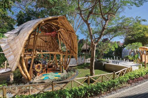 un grande edificio di bambù con un tetto in un parco di Marriott’s Bali Nusa Dua Gardens a Nusa Dua