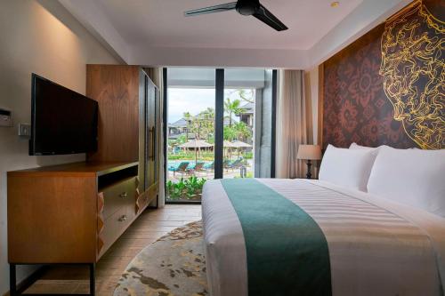 a bedroom with a bed and a television and a balcony at Marriott’s Bali Nusa Dua Gardens in Nusa Dua