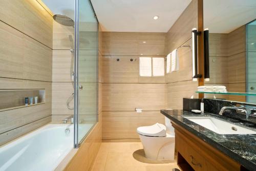 a bathroom with a tub and a toilet and a sink at Marriott’s Bali Nusa Dua Gardens in Nusa Dua