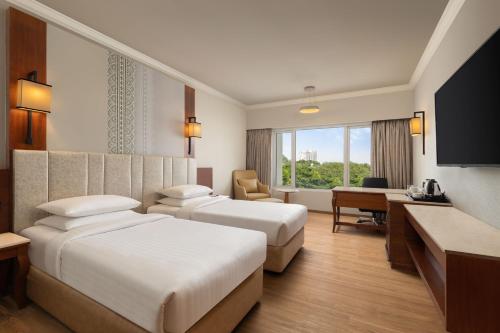 a hotel room with two beds and a desk at Courtyard by Marriott Tiruchirappalli in Tiruchirappalli