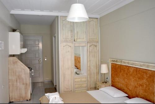 Borsalino Studios في نيدري: غرفة نوم مع سرير وخزانة خشبية كبيرة